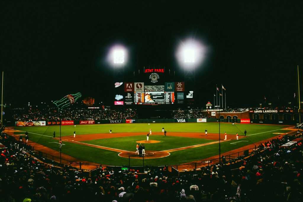 Exciting evening baseball game with fans at AT&T Park stadium under bright lights.